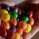Hand holding pile of Skittles candy